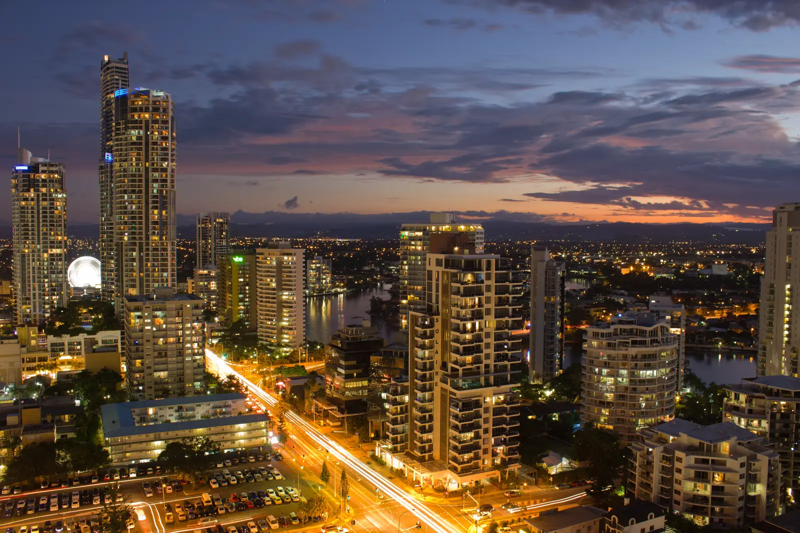 Gold Coast high-rise skyline at dusk, seen from the beach with the sand in the foreground.
