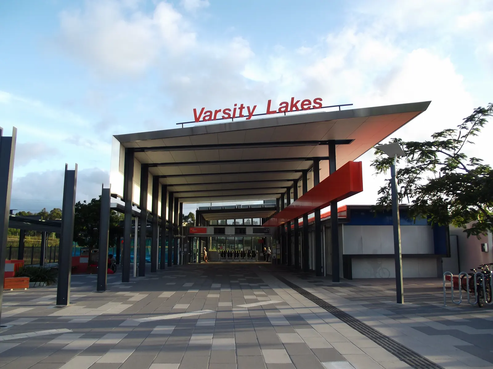 Covered glass-walled forecourt and pedestrian walkway at Varsity Lakes railway station.